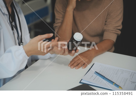Smiling woman doctor prescribing medicine giving vitamins bottle to happy senior grandmother patient sit on sofa during medical healthcare visit, older people pharmacy medication treatment concept 115358491