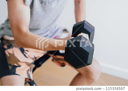 Close-up of a man doing muscle training with dumbbells at home 115358507