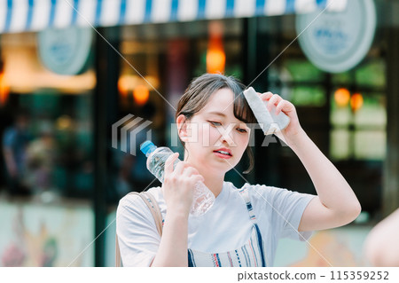 一名年輕女子忍受酷熱,用塑膠瓶為自己降溫 一名年輕女子忍受酷熱,用塑膠瓶為自己降溫 115359252