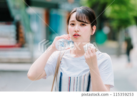 一名年輕女子忍受酷熱,用塑膠瓶為自己降溫 一名年輕女子忍受酷熱,用塑膠瓶為自己降溫 115359253