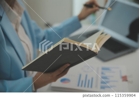 Charming Young asian businesswoman sitting on laptop computer in the office, making report calculating balance Internal Revenue Service checking document. Charming Young asian businesswoman sitting on laptop computer in the office, making report calculating balance Internal Revenue Service checking document. 115359904