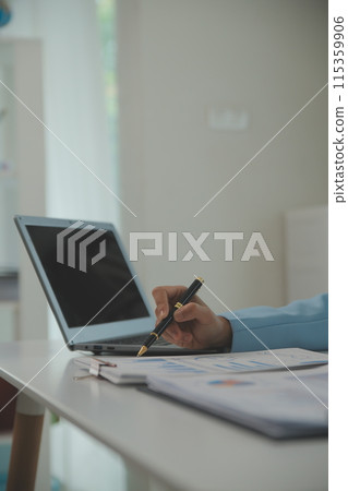 Charming Young asian businesswoman sitting on laptop computer in the office, making report calculating balance Internal Revenue Service checking document. Charming Young asian businesswoman sitting on laptop computer in the office, making report calculating balance Internal Revenue Service checking document. 115359906