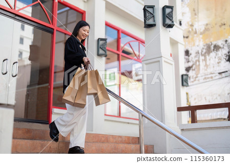 Excited Shopper Holding Shopping Bags on Black Friday Outside Store with Red Accents and Modern Architecture 115360173