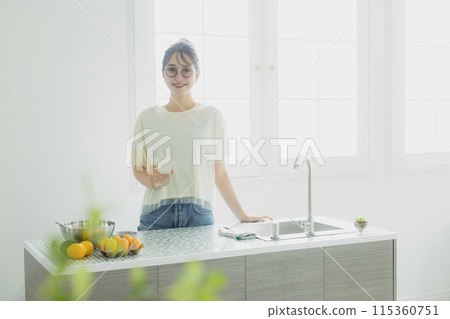 Woman drinking water in the kitchen Woman drinking water in the kitchen 115360751