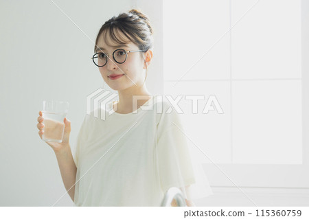 Woman drinking water in the kitchen Woman drinking water in the kitchen 115360759