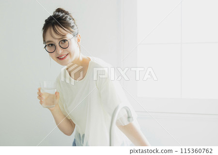 Woman drinking water in the kitchen Woman drinking water in the kitchen 115360762