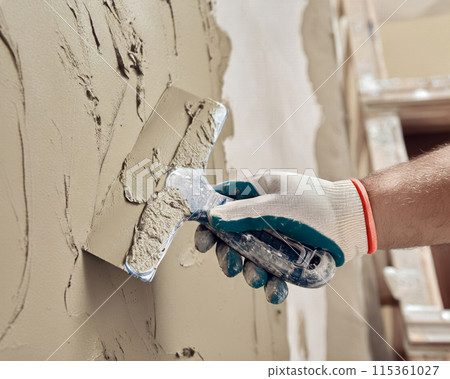 Plastering a wall with plaster in a house with a plaster knife.1 Plastering a wall with plaster in a house with a plaster knife.1 115361027