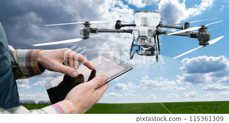 Farmer with tablet controls spreading agricultural drone that spreads fertilizer. Smart farming and precision agriculture. 115361309