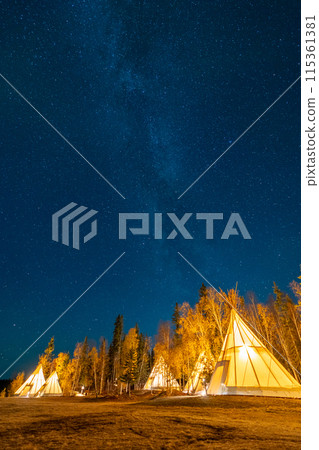 Amazing starry night sky and milky way galaxy over the light up Tipi or Tepees. Yellowknife, Northwest Territories, Canada. 115361381