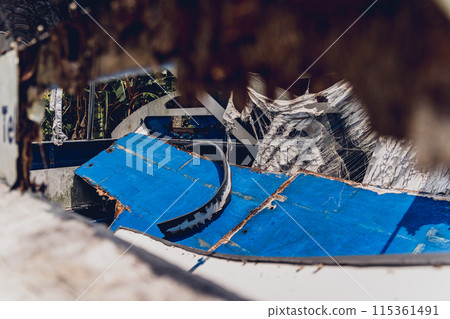Old and rusty motor boats on a landfill surrounded by tropical forest 115361491