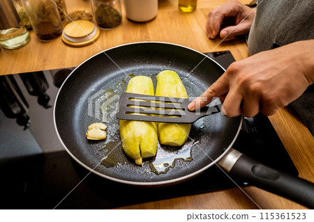 Chef at the kitchen preparing grilled eggplants with garlic Chef at the kitchen preparing grilled eggplants with garlic 115361523