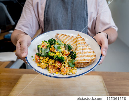 Chef at the kitchen preparing tofu scramble with vegetables Chef at the kitchen preparing tofu scramble with vegetables 115361558