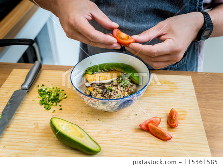 Chef at the kitchen preparing healthy quinoa bowl with avocado 115361585