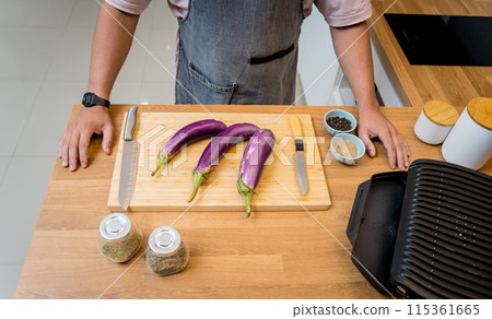 Chef at the kitchen preparing grilled eggplants with garlic Chef at the kitchen preparing grilled eggplants with garlic 115361665