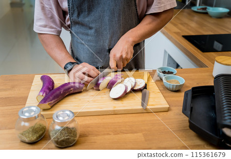 Chef at the kitchen preparing grilled eggplants with garlic Chef at the kitchen preparing grilled eggplants with garlic 115361679