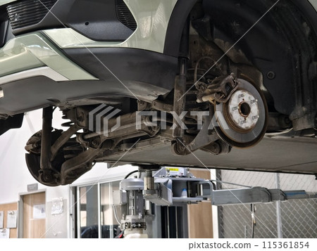 A car is raised up using a lift inside a service for maintenance A car is raised up using a lift inside a service for maintenance 115361854