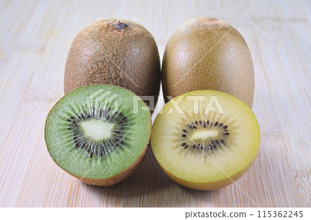 Cross-section of green and golden kiwi fruit on a cutting board Cross-section of green and golden kiwi fruit on a cutting board 115362245