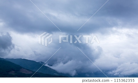 Rain clouds flowing over the mountaintop on a rainy day Rain clouds flowing over the mountaintop on a rainy day 115362355