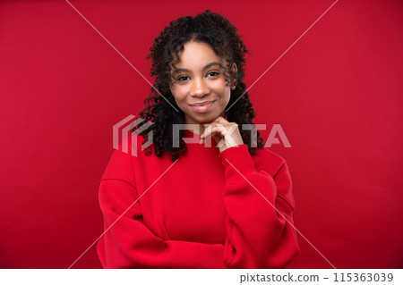 Happy emotions concept. Positive and beautiful young woman laughs poisitively looks aside with carefree face expression wears casual red sweater isolated over red studio background. 115363039