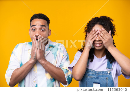 Two hipster friends smiling cheerfully while standing against a yellow background. High quality photo 115363040