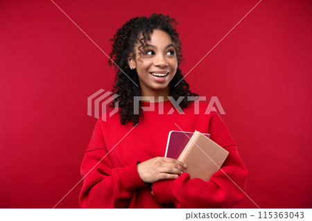 Portrait of a young girl smiling at the camera while standing against a red background. Happy black woman embracing her natural hair. Portrait of a young girl smiling at the camera while standing against a red background. Happy black woman embracing her natural hair. 115363043
