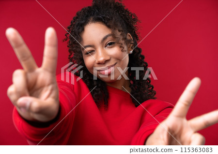 Happy emotions concept. Positive and beautiful young woman laughs poisitively looks aside with carefree face expression wears casual red sweater isolated over red studio background. Happy emotions concept. Positive and beautiful young woman laughs poisitively looks aside with carefree face expression wears casual red sweater isolated over red studio background. 115363083