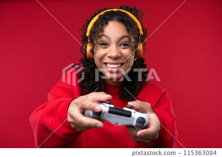 Portrait of a young girl smiling at the camera while standing against a red background. Happy black woman embracing her natural hair. Portrait of a young girl smiling at the camera while standing against a red background. Happy black woman embracing her natural hair. 115363084