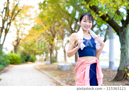 A young woman jogging along a road lined with autumn trees Diet Bodybuilding 115363121