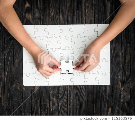 hands completing wthite puzzle with the last piece hands completing wthite puzzle with the last piece 115363579