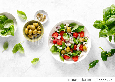 Fresh healthy vegetable Mediterranean salad of feta cheese, tomato, olives, green pepper and green basil leaves, top view Fresh healthy vegetable Mediterranean salad of feta cheese, tomato, olives, green pepper and green basil leaves, top view 115363797