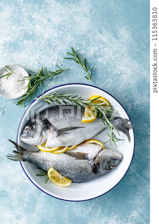 Fresh raw dorado fish cooking with lemon and rosemary. Sea bream, dorado. Seafood, healthy food. Top view Fresh raw dorado fish cooking with lemon and rosemary. Sea bream, dorado. Seafood, healthy food. Top view 115363810