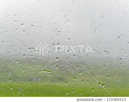 Water beads on glass, evidence of rainfall against a green backdrop. Water beads on glass, evidence of rainfall against a green backdrop. 115364315