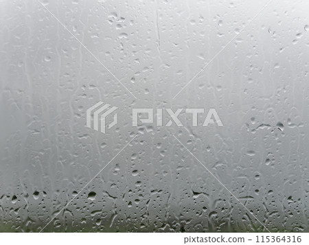 A close-up of a window pane speckled with water droplets, hinting at recent rainfall or misty conditions. 115364316