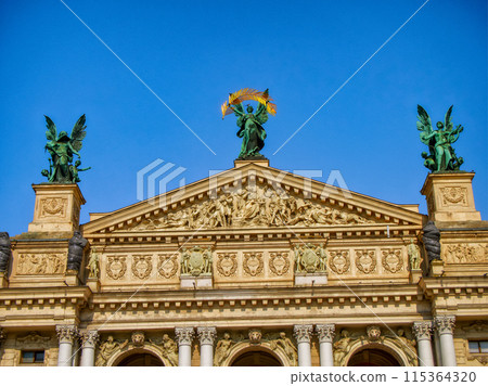 Angelic Statues. Angelic statues adorn a classical structure, set against a vibrant sky, reflecting cultural and artistic heritage, facade of the Lviv Opera building. 115364320