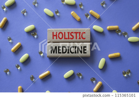 Holistic Medicine symbol. Concept word. Holistic Medicine on wooden blocks. Beautiful purple background with pills. Medicine and Holistic Medicine concept. Copy space 115365101