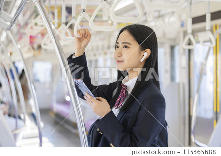 一名女高中生拿著智慧型手機、戴著耳機搭火車上學的照片 115365688