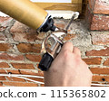 Window installation. The process of insulating windows with construction foam. A builder's hand seals the cracks between the building and the window frame. Construction and insulation of the building. 115365802