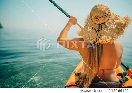 Woman in kayak back view. Happy woman with long hair in a swimsuit and hat floating in kayak on the sea. Summer holiday vacation. Summer holidays vacation at sea. 115366193