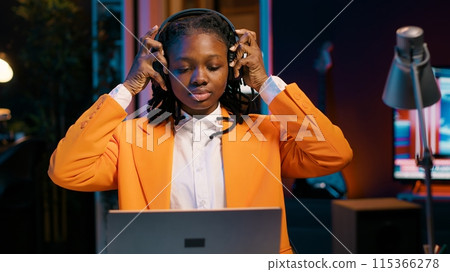 University student playing music on headphones to focus easily on college tasks and homework, writing essay for literature class. Girl enjoying modern relaxing tunes while she is working. Camera A. University student playing music on headphones to focus easily on college tasks and homework, writing essay for literature class. Girl enjoying modern relaxing tunes while she is working. Camera A. 115366278
