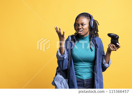 Annoyed BIPOC young girl raging after receiving game over screen, holding controller. Mad african american teenager frustrated after losing videogame, playing with gamepad, studio background Annoyed BIPOC young girl raging after receiving game over screen, holding controller. Mad african american teenager frustrated after losing videogame, playing with gamepad, studio background 115366457