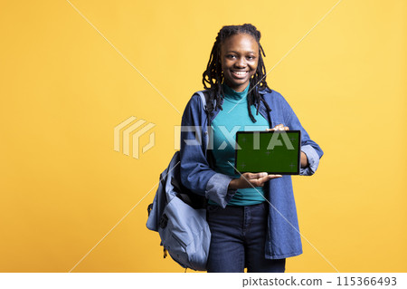 Happy african american girl laughing while presenting tablet with isolated screen display, studio background. Cheerful BIPOC person has fun during promotion for chroma key device 115366493