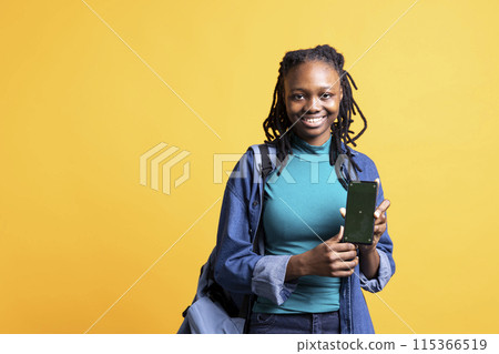 Jolly african american woman presenting smartphone with green screen display, isolated over studio background. Joyous BIPOC person creating promotion with blank copy space mockup phone Jolly african american woman presenting smartphone with green screen display, isolated over studio background. Joyous BIPOC person creating promotion with blank copy space mockup phone 115366519