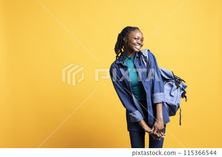 Upbeat african american teenager in giddy stance feeling joyous, isolated over studio background. Portrait of cheerful BIPOC young girl acting silly, showing positive demeanor 115366544