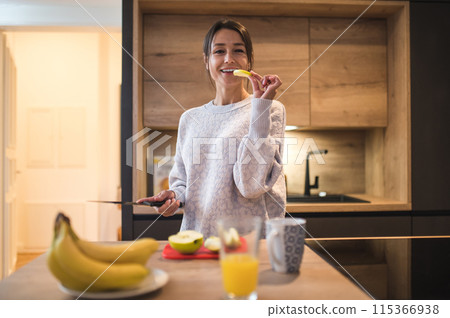 Cute young woman cooking breakfast and looking contented Cute young woman cooking breakfast and looking contented 115366938