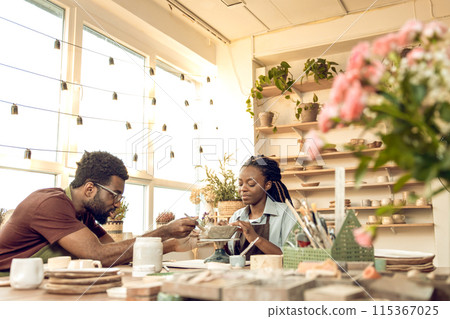 Two people working with pottery and looking involved 115367025