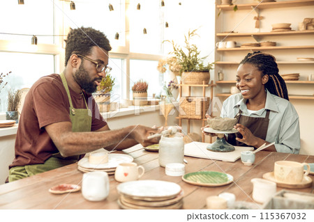 Cute dark-skinned woman having a pottery master class with a male sculptor 115367032