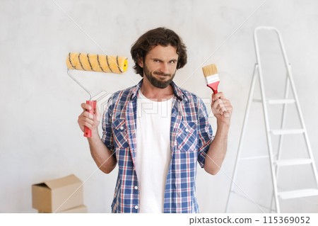 Confused Man Holding Paint Supplies for DIY Home Renovation 115369052