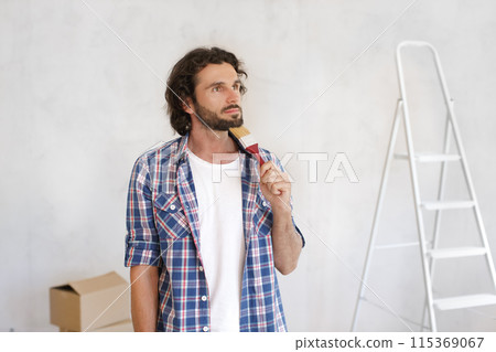 Thoughtful Man Holding Paintbrush Planning Home Renovation Thoughtful Man Holding Paintbrush Planning Home Renovation 115369067