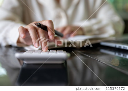 A cropped image of a businesswoman or female accountant using a calculator while working at her desk A cropped image of a businesswoman or female accountant using a calculator while working at her desk 115370572