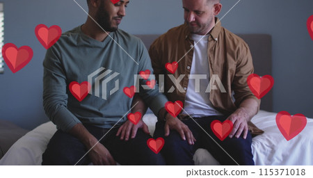 Image of red hearts over diverse male couple sitting on bed 115371018
